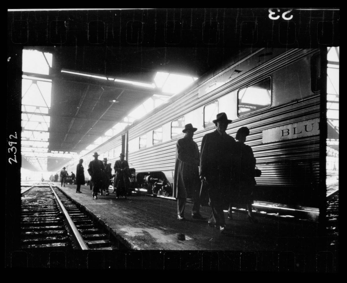 Men, probably commuters, walking along a platform next to a train
